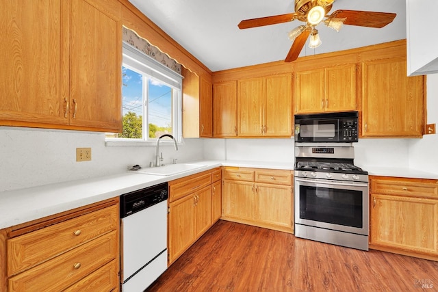 kitchen with a sink, white dishwasher, black microwave, stainless steel gas stove, and wood finished floors