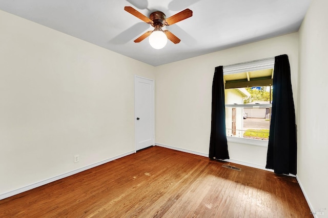 spare room featuring baseboards, visible vents, wood finished floors, and ceiling fan