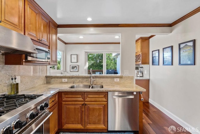 kitchen with brown cabinetry, appliances with stainless steel finishes, dark wood-style floors, and a sink