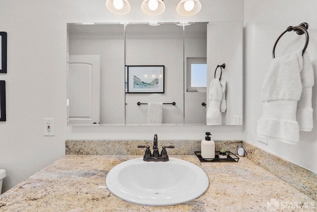 bathroom featuring vanity, crown molding, and toilet