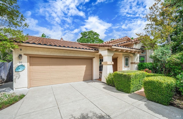 mediterranean / spanish-style home with a garage, stucco siding, driveway, and a tiled roof