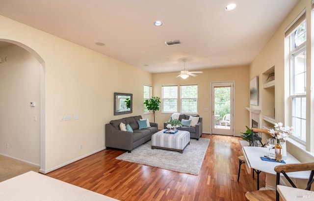 living room with baseboards, arched walkways, a ceiling fan, and wood finished floors
