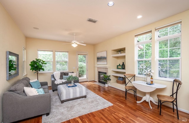 living area with visible vents, wood finished floors, a healthy amount of sunlight, and built in shelves
