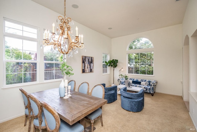 carpeted dining room with arched walkways, baseboards, and a chandelier