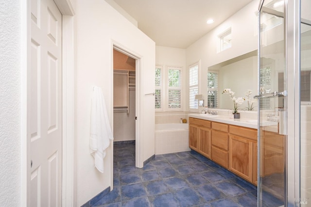 full bathroom featuring a bath, a shower stall, vanity, tile patterned floors, and a spacious closet