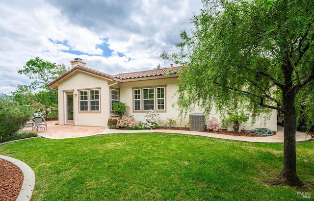 back of property featuring a chimney, a tile roof, a lawn, a patio, and stucco siding