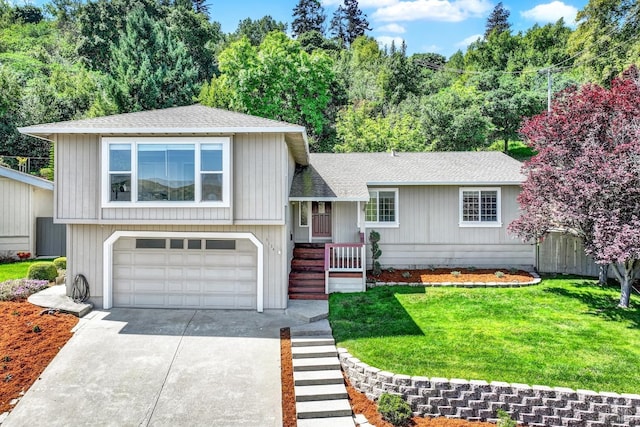 tri-level home featuring driveway, a front yard, fence, an attached garage, and a shingled roof