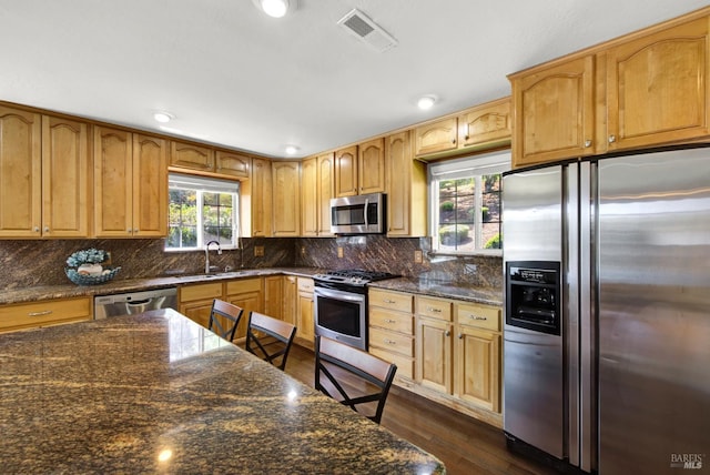 kitchen featuring dark wood-style flooring, visible vents, tasteful backsplash, a sink, and stainless steel appliances