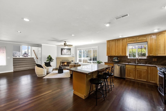 kitchen featuring visible vents, appliances with stainless steel finishes, a fireplace, a sink, and open floor plan