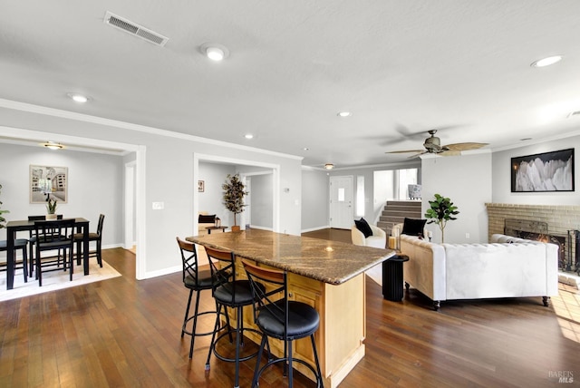 kitchen with visible vents, ornamental molding, dark wood-style flooring, and a kitchen breakfast bar