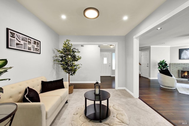 living room with baseboards, recessed lighting, a brick fireplace, and wood finished floors