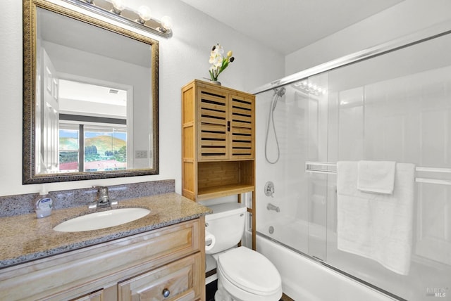 full bath featuring vanity, bath / shower combo with glass door, and toilet