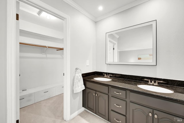 bathroom with double vanity, a sink, a spacious closet, and ornamental molding
