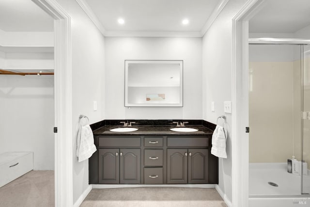 bathroom with double vanity, ornamental molding, a shower stall, and a sink