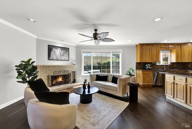 living room with ceiling fan, a brick fireplace, baseboards, dark wood-style floors, and ornamental molding