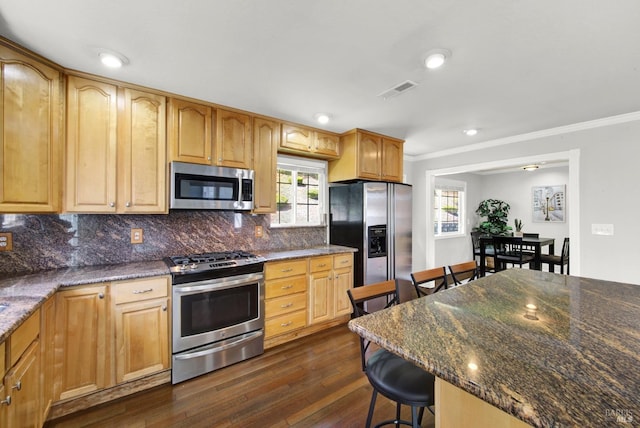 kitchen with decorative backsplash, crown molding, appliances with stainless steel finishes, dark wood-style floors, and a breakfast bar