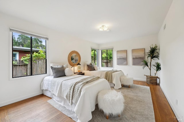 bedroom featuring baseboards, visible vents, and wood finished floors