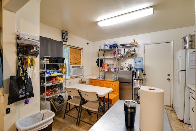 kitchen with stone finish flooring, cooling unit, and freestanding refrigerator