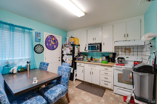 kitchen featuring freestanding refrigerator, stainless steel microwave, under cabinet range hood, white cabinets, and white range with electric stovetop
