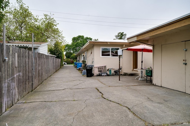 view of property exterior featuring stucco siding, a patio area, and fence