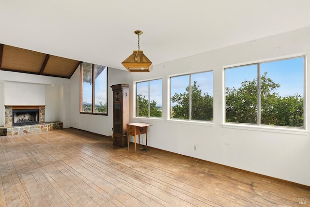 unfurnished living room featuring light wood finished floors and a stone fireplace