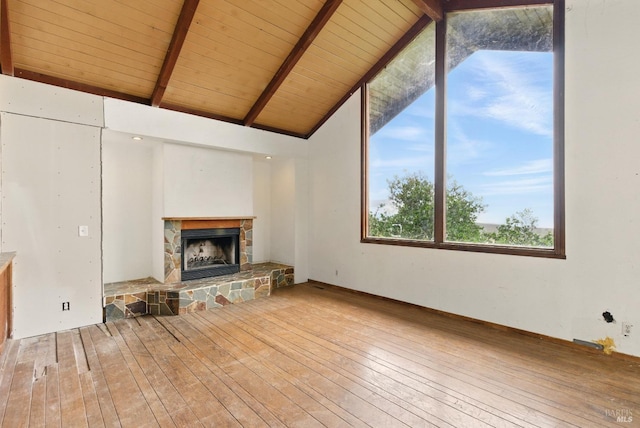unfurnished living room with a stone fireplace, vaulted ceiling with beams, and hardwood / wood-style flooring