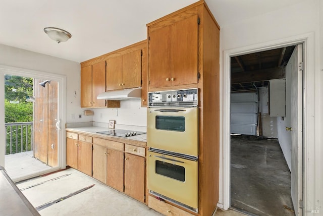 kitchen featuring black electric stovetop, under cabinet range hood, concrete floors, light countertops, and double oven