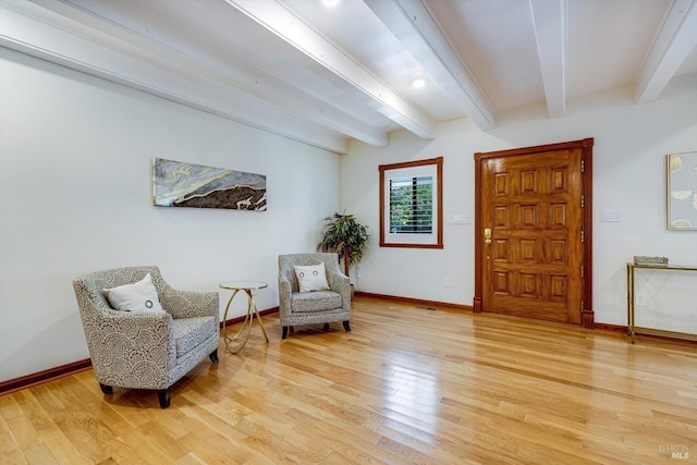 sitting room with light wood-style flooring, beamed ceiling, and baseboards