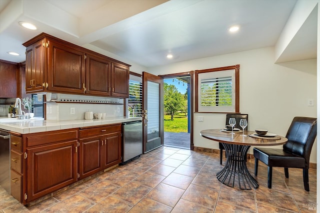 kitchen with recessed lighting, tile counters, dishwasher, a sink, and baseboards