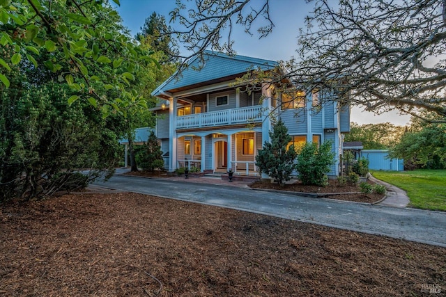 greek revival inspired property with a porch, driveway, and a balcony