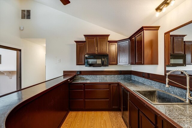kitchen with visible vents, black microwave, tile counters, and a sink