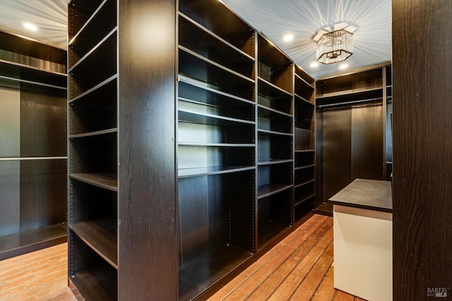 walk in closet with hardwood / wood-style floors and an inviting chandelier