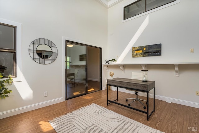office featuring a towering ceiling, wood finished floors, and baseboards