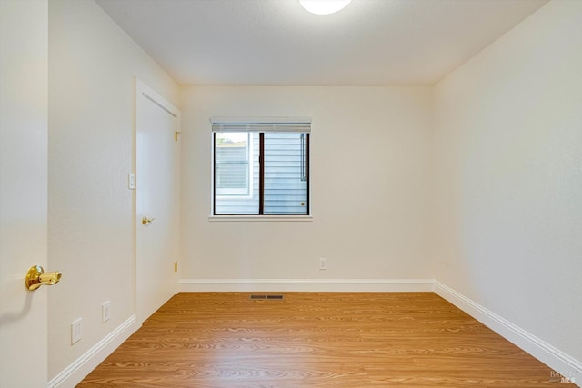 unfurnished room with baseboards, light wood-type flooring, and visible vents