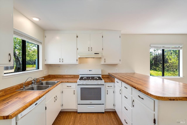 kitchen featuring a sink, under cabinet range hood, a peninsula, white appliances, and white cabinets