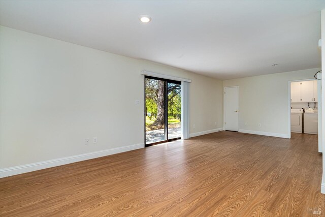 spare room featuring light wood-type flooring, washing machine and clothes dryer, and baseboards