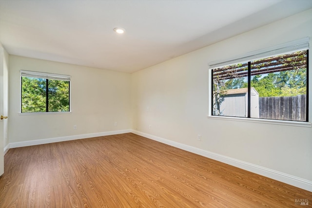 empty room with light wood-type flooring, recessed lighting, a healthy amount of sunlight, and baseboards