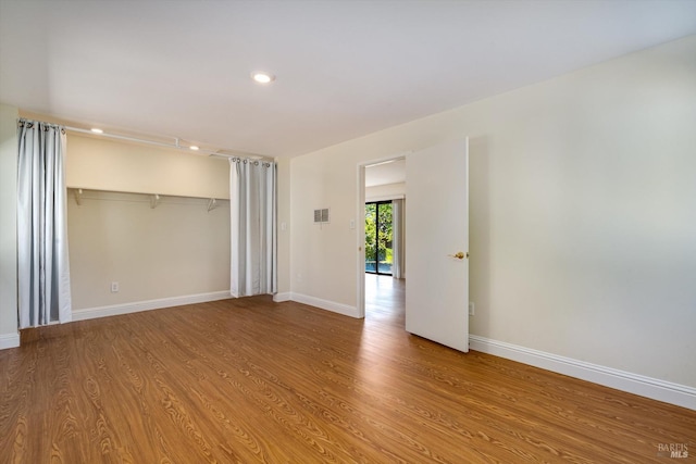 unfurnished bedroom with wood finished floors, baseboards, and a closet