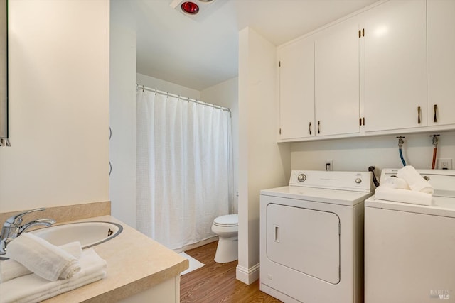 laundry room with a sink, laundry area, light wood-style flooring, and washing machine and dryer