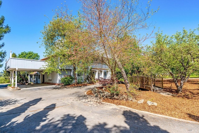 view of property hidden behind natural elements featuring a carport and driveway