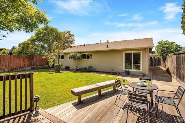 rear view of house with a fenced backyard, stucco siding, a lawn, and a deck