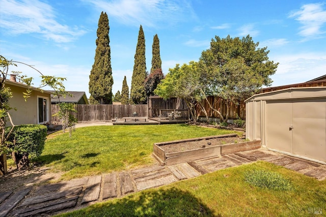 view of yard with a storage unit, a fenced backyard, a vegetable garden, and an outdoor structure