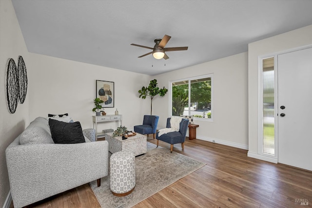 living area featuring a ceiling fan, baseboards, and wood finished floors