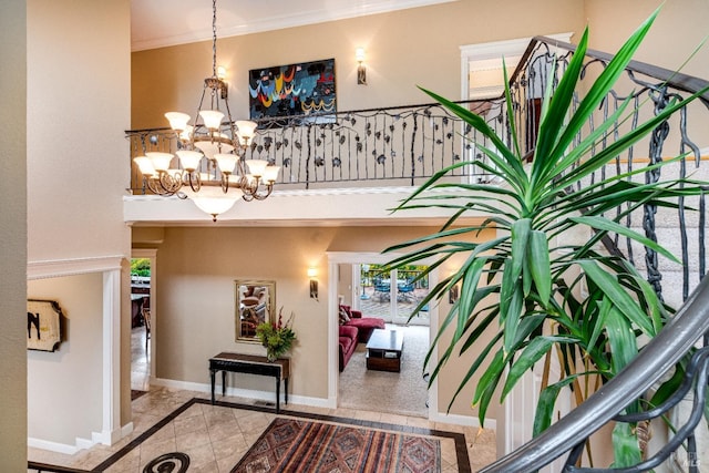 foyer entrance featuring baseboards, ornamental molding, a notable chandelier, and tile patterned flooring