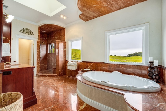 bathroom with walk in shower, a tub with jets, vanity, marble finish floor, and a skylight