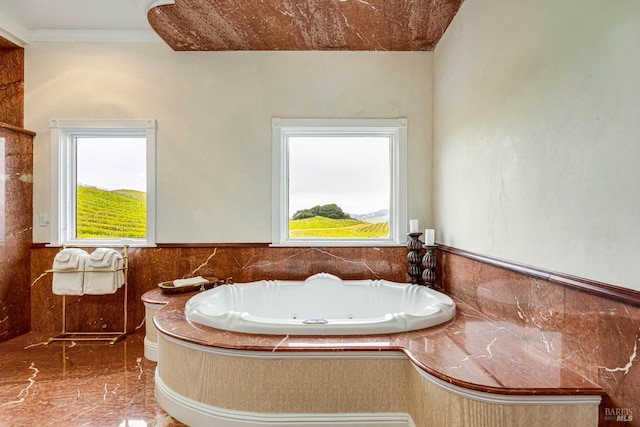 bathroom featuring a tub with jets, crown molding, marble finish floor, and wainscoting