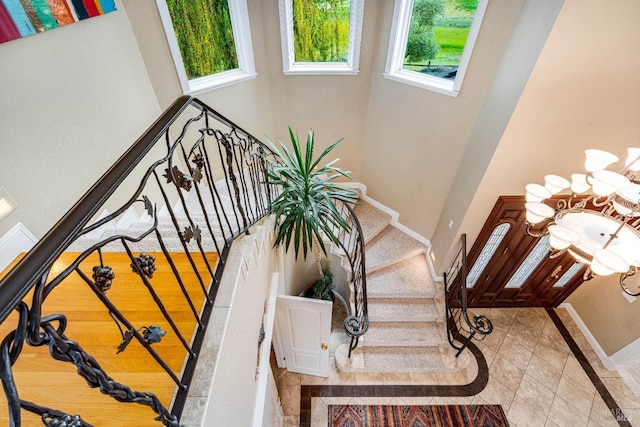 stairway with an inviting chandelier, a high ceiling, and baseboards
