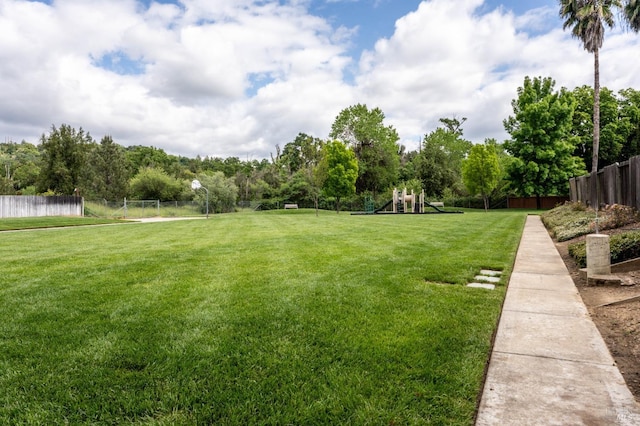 view of yard featuring playground community and fence