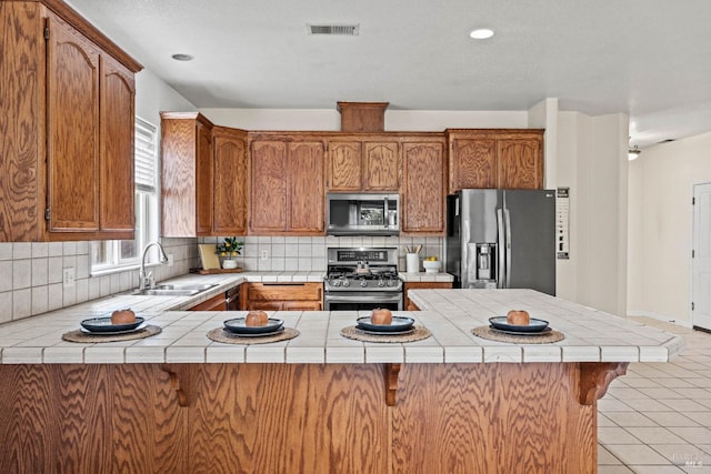 kitchen with tile countertops, a sink, stainless steel appliances, and visible vents