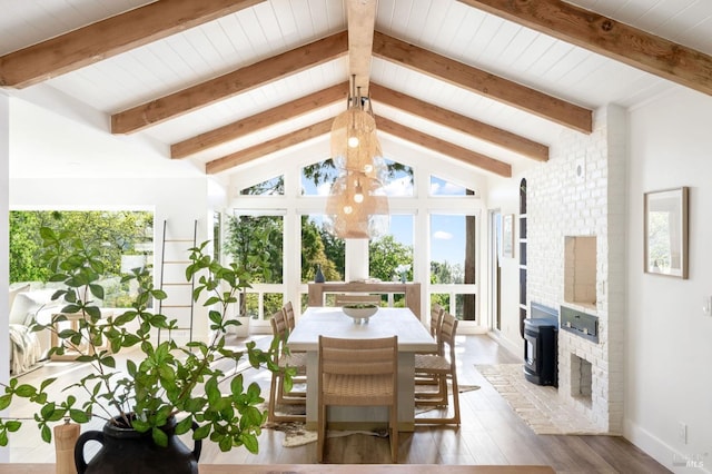 sunroom / solarium with beam ceiling, a wealth of natural light, and a wood stove
